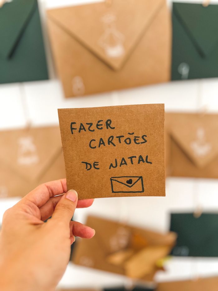 Mão segurando um cartão escrito: fazer cartões de Natal